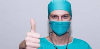 stenose chirurg met ok-muts en mondneusmasker maakt ok-gebaar (duim omhoog)