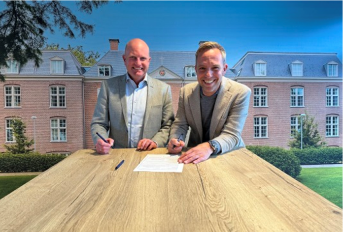 Contract-ondertekening door vertegenwoordigers van CBRE en Domus Valuas. Op de achtergrond een moi zorggebouw.